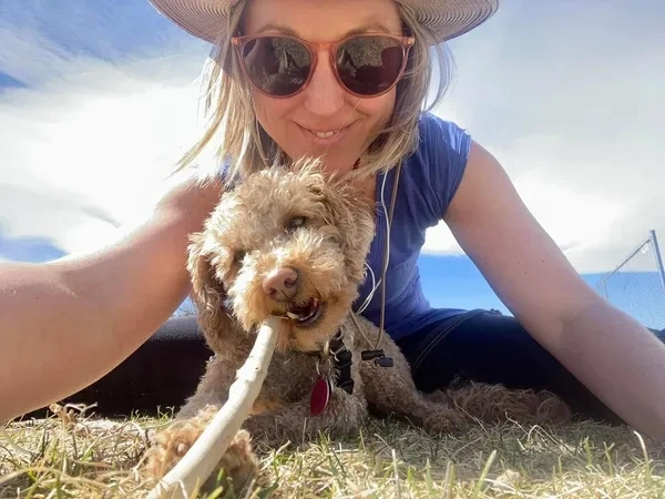 Emily Wishall enjoying time outdoors with her dog, Tula, in a joyful moment of connection and play.